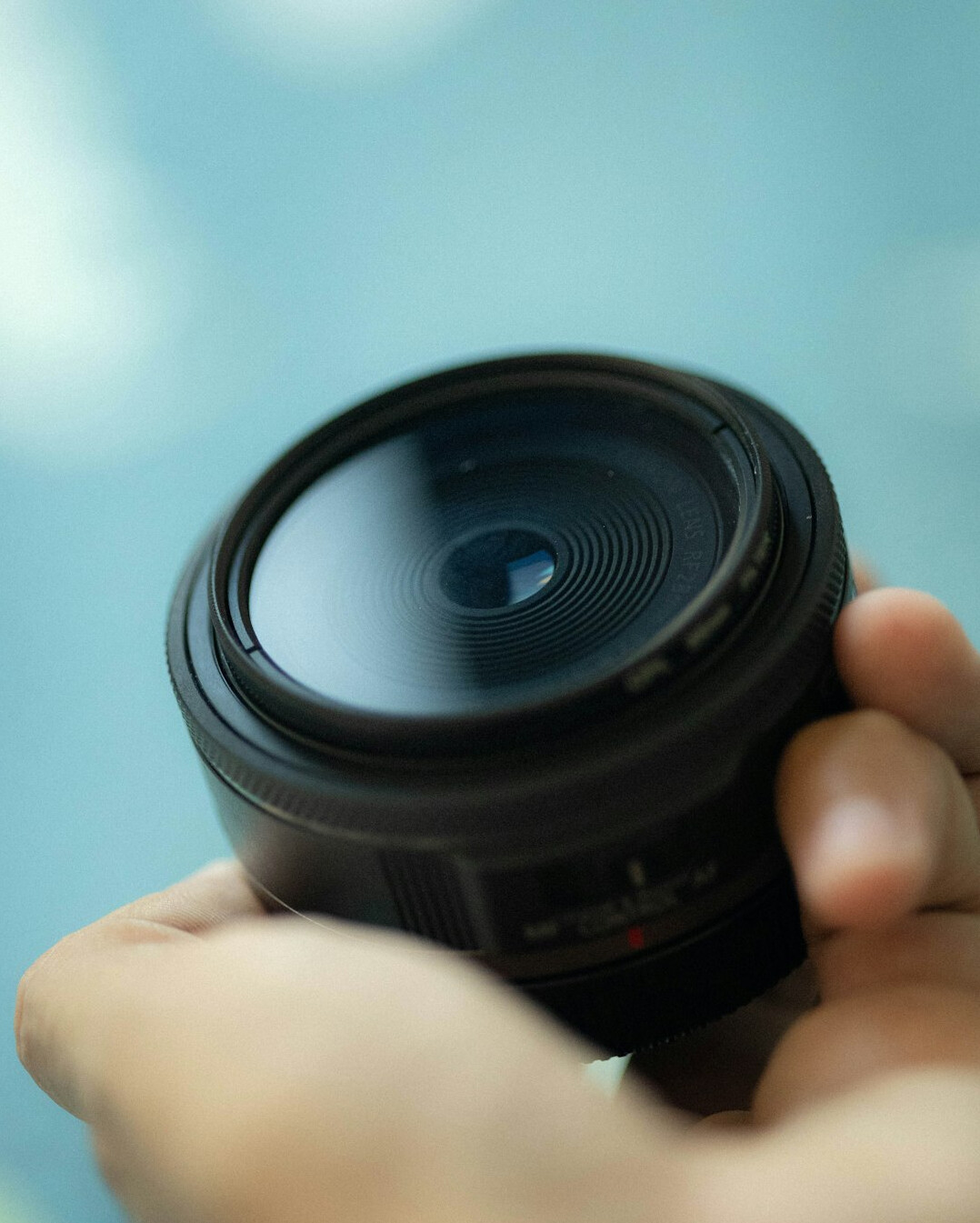 Close-up of a professional broadcast camera lens with an operator's hand adjusting focus